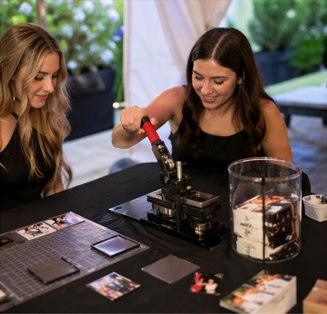Two PocketJoy staff members pressing custom photo magnets live at an outdoor event